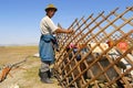 Mongolian man assembles yurt in steppe, circa Harhorin, Mongolia.