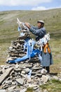 Mongolian man ties ribbon to sacred shrine