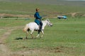 Mongolian man wearing traditional costume rides on horse back in a steppe in Kharkhorin, Mongolia. Royalty Free Stock Photo