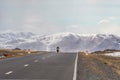 Mongolian motorcyclist in the distance on a mountain highway. Snow straight winter road through the hills. Mountain road on a Royalty Free Stock Photo