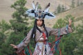 Mongolian woman in shaman and witch costume dances on stage in the mountains. Tyva folk dances