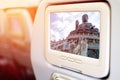 Monitor in front of passenger seat showing Tian Tan Giant Buddha in blue sky