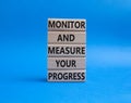 Monitor and Measure your Progress symbol. Wooden blocks with words Monitor and Measure your Progress. Beautiful blue background.