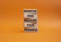 Monitor and Measure your Progress symbol. Wooden blocks with words Monitor and Measure your Progress. Beautiful orange background
