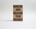 Monitor and Measure your Progress symbol. Wooden blocks with words Monitor and Measure your Progress. Beautiful white background.