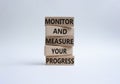 Monitor and Measure your Progress symbol. Wooden blocks with words Monitor and Measure your Progress. Beautiful white background.