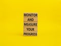 Monitor and Measure your Progress symbol. Wooden blocks with words Monitor and Measure your Progress. Beautiful yellow background