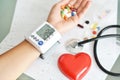 Monitoring of blood pressure of hypertensive patient, with red heart, stethoscope and pills on electrocardiogram Royalty Free Stock Photo