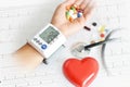 Monitoring of blood pressure of hypertensive patient, with red heart, stethoscope and pills on electrocardiogram Royalty Free Stock Photo