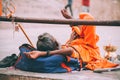 monk in bright orange clothing resting