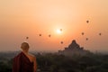 Monk looking at hot air balloons at sunrise at Bagan temple, Burma, Myanmar