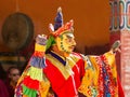 monk performs a masked and costumed sacred dance of Tibetan Buddhism, another monks play ritual music during the Cham Dance