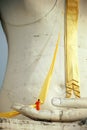 A monk preparing yellow robe for Buddha statue.