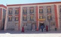 Monk in a red robe walks towards entrance of a bookshop in Sakya monastery.