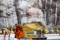 Monk respect praying and gild cover with gold leaf at Lord Buddha image appearing on a cave wall Royalty Free Stock Photo