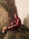 Monk sitting on stone having drink