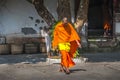 A Monk wearing his traditional orange/yellow robe is leaving a monastery in Luang Prabang, Laos