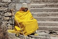 Monk in yellow robe with a pilgrim`s staff is resting