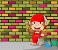 The monkey holding a pail of pain and brush for coloring the wall and bricks Royalty Free Stock Photo