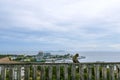 A monkey sitting on a wall with a view of the sea and sky behind Khao Sam Muk in Chonburi Province Royalty Free Stock Photo