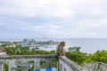 A monkey sitting on a wall with a view of the sea and sky behind Khao Sam Muk in Chonburi Province Royalty Free Stock Photo