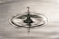 Monochromatic image of water drop balanced at top of splash. High speed photography