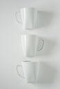 3 white coffee mugs on white background in a vertical row, empty copy space Royalty Free Stock Photo