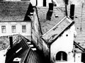 Monochrome aerial closeup view of old sloped clay roofs in urban setting. chimneys and antennas