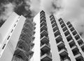 Monochrome angled detail view of an old 1960s white concrete apartment building with steps and balconies against sky and clouds