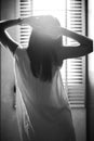 Monochrome back portrait of girl puts her hands on the head with sunlight and blurred curtain in background