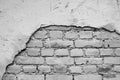 Monochrome brick wall with a hole from the fallen off plaster