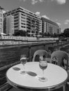 Monochrome cityscape with a pleasure boat with two glasses of white wine on the table