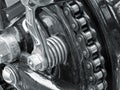 Monochrome close up of the drive chain on a black vintage motorbike with chrome fixtures and steel bolts