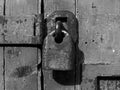 monochrome close up of an old rusty closed padlock and hasp on a distressed wooden plank door Royalty Free Stock Photo
