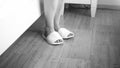 Black and white closeup image of female feet wearing slippers at bed in hotel Royalty Free Stock Photo