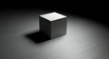 Monochrome cube stands alone in dark studio lighting Royalty Free Stock Photo