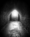 Monochrome dark image of an old underground pedestrian foot tunnel with an arched roofs stone walls and a cracked floor with a Royalty Free Stock Photo