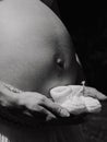 Monochrome of a happy expectant mother holding a pair of baby shoes on her belly Royalty Free Stock Photo