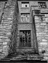 Monochrome image of broken windows in an empty abandoned vandalized old stone building