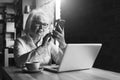 Monochrome image. Businesswoman is sitting at table in front of laptop and using smartphone.Education for adults