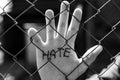 Monochrome image, caucasian man behind wired fence showing hes palm