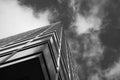 Monochrome image of a modern skyscraper reaching into sky filled with textured clouds, showcasing bold architecture and Royalty Free Stock Photo