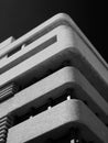 Monochrome image of an old brutalist concrete tower block with rounded textured corners against a dark sky