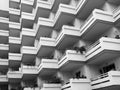 Monochrome image of repeating balconies on large modern concrete apartment building with house plants