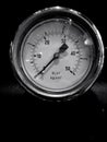 Monochrome image of a round pressure meter with a numbered dial on a dark background Royalty Free Stock Photo