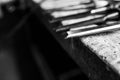 Monochrome image, sharp chisels in row on aged old oak wood workbench, shallow depth of field Royalty Free Stock Photo