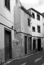 monochrome image of a typical quiet empty street in funchal madeira with old traditional houses painted in faded peeling paint and