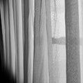 Monochrome photo of a bright sunlit window with sheer white curtains billowing in the breeze Royalty Free Stock Photo