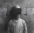 Monochrome photo of man in grey headgear with face covered by box