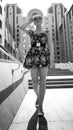 Black and white portrait of beautiful smiling young woman posing on stone stairs against modern building at bright sunny Royalty Free Stock Photo